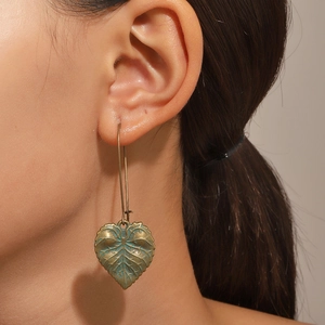 Gros plan de boucles d'oreilles feuilles en bronze vintage avec patine verte sur un mannequin