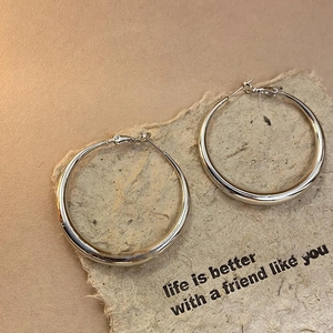 Macro shot of silver twisted geometric hoop earrings on a vintage paper with text