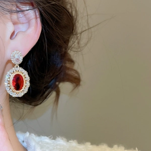 Close-up of vintage style oval red gemstone earrings with gold plating and zircons