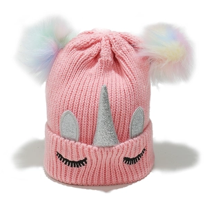 Détail du bonnet licorne rose tricoté avec pompons arc-en-ciel et détails pailletés