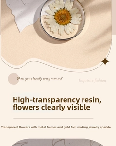Detail of clear resin pendant with dried daisy and gold leaf in metal frame