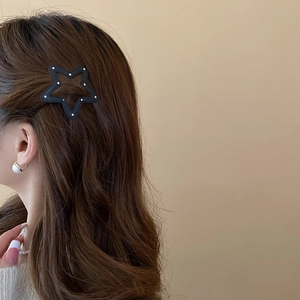 Detail shot of a black star-shaped hair clip with white polka dots on brown wavy hair