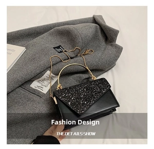 Detail der schwarzen matten Handtasche mit Glitzerklappe, goldenem Ringgriff und Kette