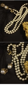 Dettaglio macro di collana di perle a strati con chiusura a rondine dorata e ciondolo