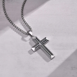Macro detail of silver stainless steel cross pendant and braided rope chain