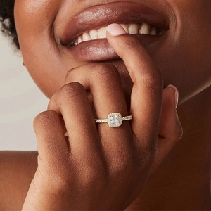 Close-up of square halo diamond ring in gold finish worn on a finger for wedding