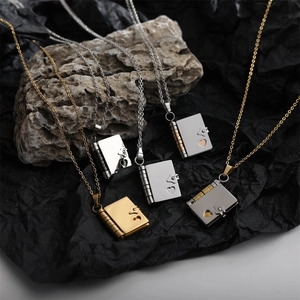 Polished titanium steel book locket necklaces in gold and silver on natural rock