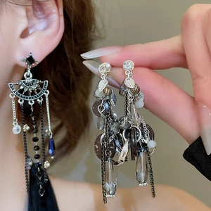 Close-up of bohemian silver drop earrings with dark crystals and long tiered tassels
