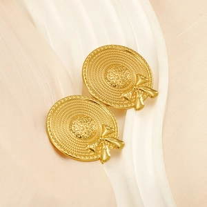 Detailed close-up of golden sun hat earrings with concentric textures and bow accents
