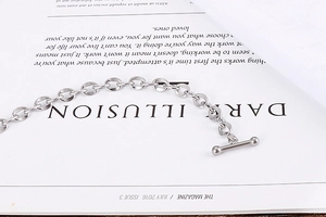 Macro detail of silver stainless steel chain bracelet with a classic metal T-bar toggle clasp