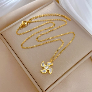 Detailed macro view of windmill pendant necklace with sparkling zircons in gold finish