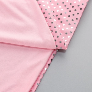 Close-up of pink fabric featuring silver sequin polka dots and mesh texture details