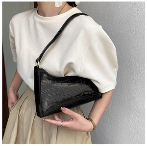 Detail shot of black crocodile texture faux leather baguette bag worn by model