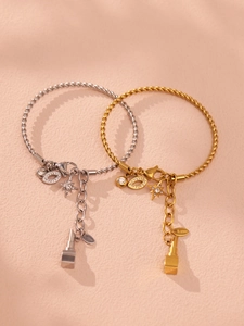 Detail von Gold- und Silber-Kabelarmbändern mit Sternen- und Augenanhängern auf beigem Grund