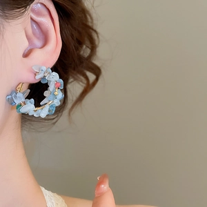 Detail of handmade gold hoop earring with natural blue stones and pearls on ear