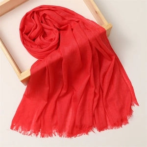 Detailed shot of soft red linen scarf with fringe edges draped over a wooden frame