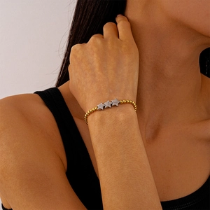 Gros plan d'un bracelet vintage à perles dorées avec pendentifs étoiles sur le poignet d'une femme