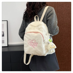 Dettaglio dello zaino in peluche bianco con ricamo a cuore rosa e ciondolo a nuvola