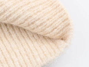 Close-up of beige jacquard knit texture showing soft fleece material and fluffy yarn