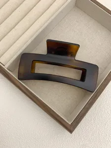 Detailed view of a large square tortoiseshell claw clip on a luxury wooden jewelry box