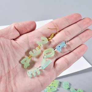Detailed macro view of resin LOVE letter earrings with glitter and metal hooks
