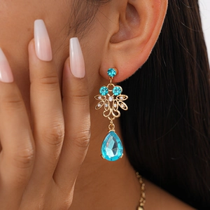 Close-up of golden vintage flower earrings with light blue water drop gemstone pendants