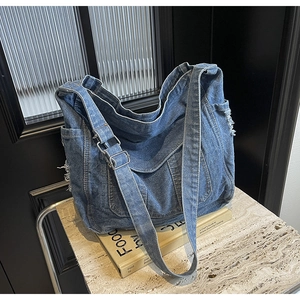 Détail du sac bandoulière en denim bleu avec bords effilochés et boucle métallique