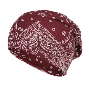 Detail of burgundy knit beanie featuring white paisley print on soft stretchy fabric