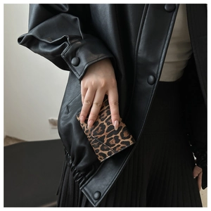 Primo piano della mini borsa leopardata tenuta da una modella con giacca di pelle nera