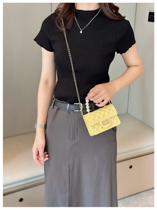Model wearing a yellow quilted mini handbag with pearl handle and golden chain strap