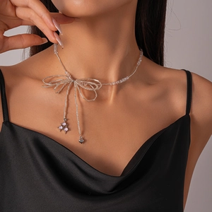 Detail of beaded bow necklace with purple beads and heart charm on a model's neck