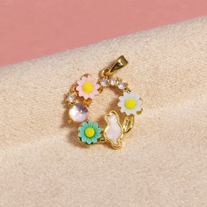 Detailed macro view of a gold pendant featuring enamel flowers and a pink bunny charm