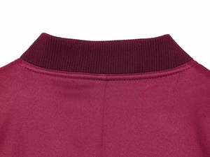 Macro detail of wine red jacket neckline with ribbed collar and premium twill texture