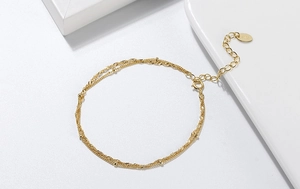 Detail of a gold double-layer chain bracelet with small beads and lobster clasp closure