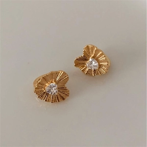 Detail of gold heart earrings with heart-shaped cubic zirconia and textured surface
