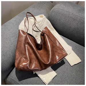 Detail view of large dark brown retro tote bag with soft leather texture on sofa