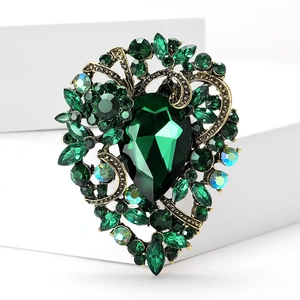Macro detail of emerald green gemstone brooch with vintage gold filigree and crystals