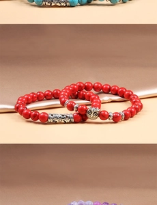 Detailed close-up of red beaded bracelet featuring an owl pendant and hollow floral charm