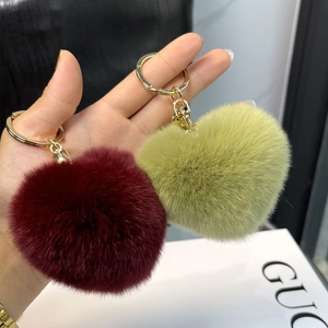 Close-up of heart-shaped faux fur keychains in burgundy and light green with gold rings