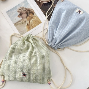 Detail of drawstring plaid canvas backpack with beaded cords in light blue and green
