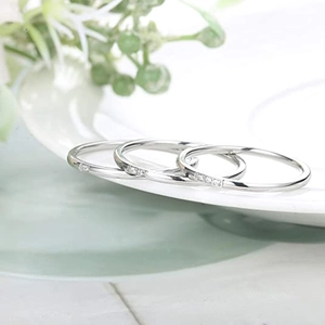 Close-up of three minimalist silver stackable rings with small zircons on a white plate