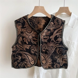 Close-up of ethnic paisley embroidered vest with intricate jacquard texture and braided edges