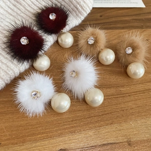 Detail of plush fur ball earrings with pearls and rhinestones in autumn colors