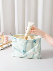 Striped canvas makeup bag with blue bow embroidery and secure top zipper closure