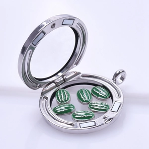 Macro detail of a silver magnetic glass locket partially open showing tiny green watermelon charms