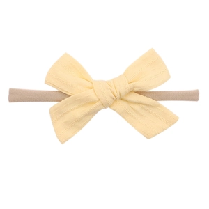 Close-up of soft beige nylon headband featuring a textured light yellow fabric bow