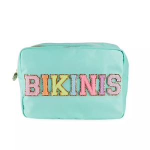 Detail of waterproof nylon cosmetic bag with shiny BIKINIS glitter patch and gold zipper