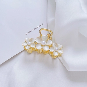 Elegant gold metal flower hair claw clip with white enamel petals and pearl center