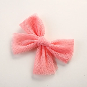 Close-up of pink mesh bow hair clip with intricate textile texture on plain background