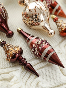 Detailed macro view of champagne and burgundy Christmas ornaments on white knit fabric